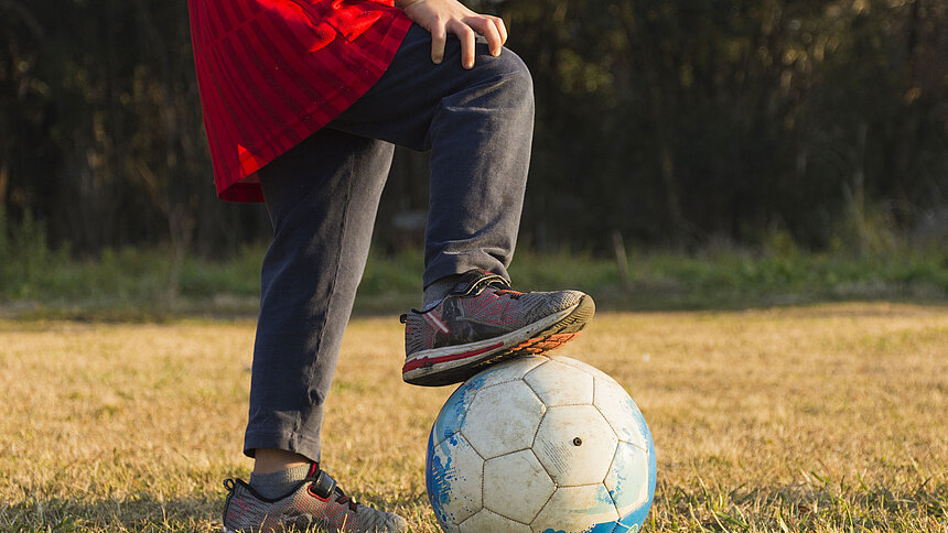 Gros plan sur le pied d'un enfant sur un ballon de foot