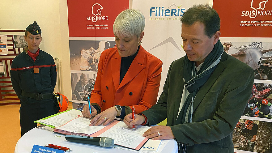 Marie-Hélène Quatreboeufs et Nicolas Blanchart, debout, signent des papiers