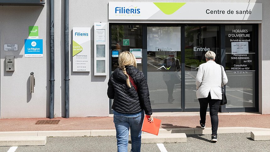 Deux patientes avancent devant la porte d'entrée et façade du centre La Ricamarie
