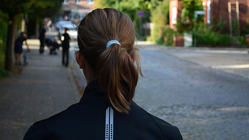 Une adolescente, de dos, marche dans la rue.
