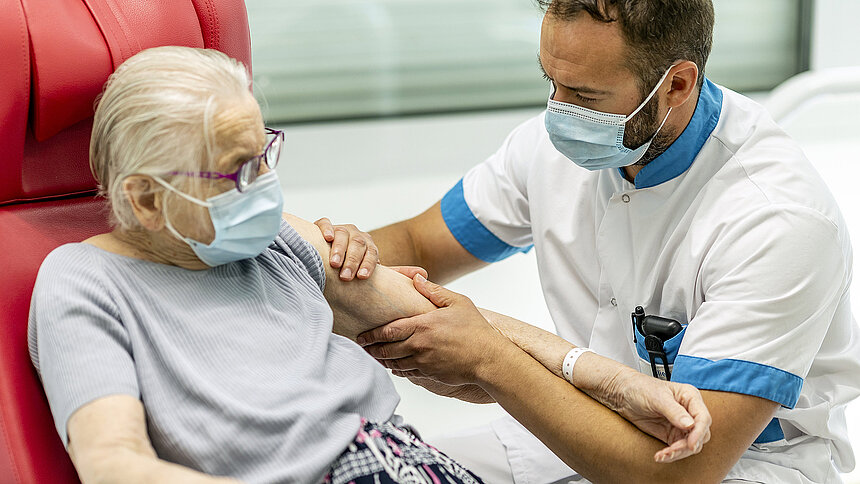 Un infirmier ausculte le bras d'une personne âgée