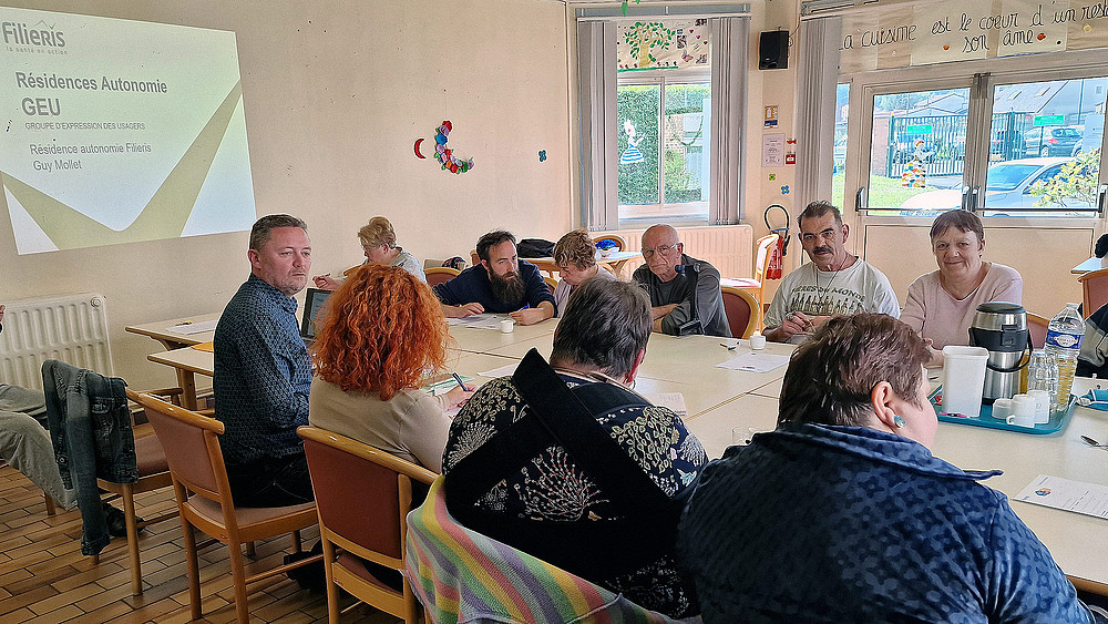 Une dizaine de personnes autour d'une table, en train de discuter