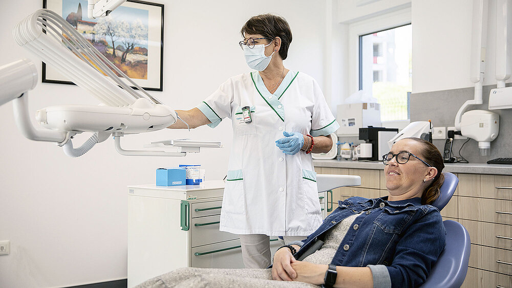 Une dentiste debout et une patiente sur la chaise de soins