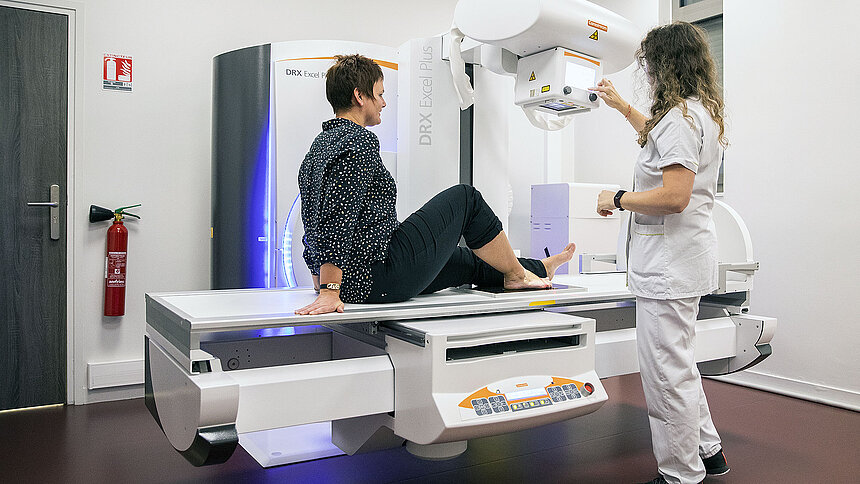 Une patiente assise sur la table de radiologie, avant son examen.