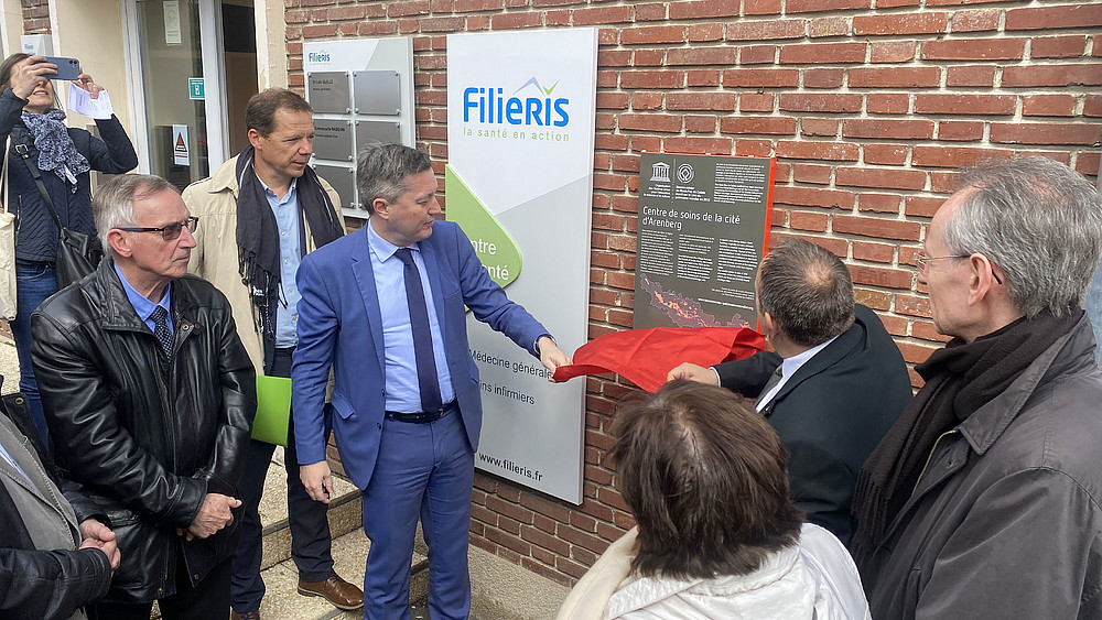 Plusieurs personnes applaudissent devant la plaque de l'UNESCO
