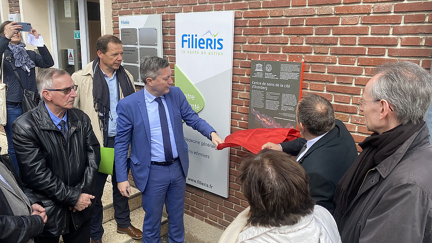 Plusieurs personnes applaudissent devant la plaque de l'UNESCO