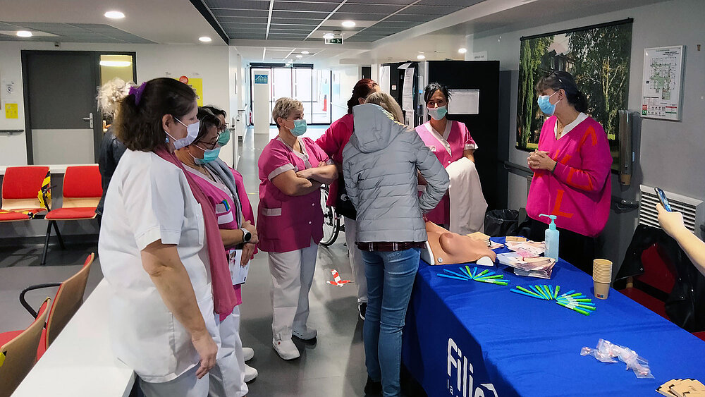 Des aides soignantes se tiennent autour d'une table de prévention contre le cancer du sein.