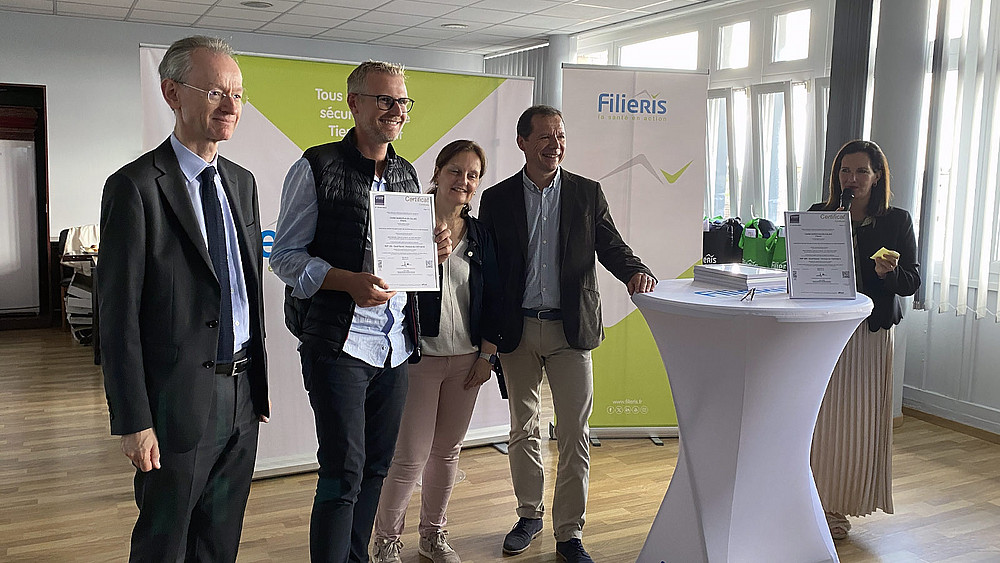 Un professionnel Filieris tient le certificat dans ses mains, entouré de Gilles de Lacaussade et Nicolas Blanchart