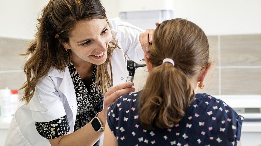 Une femme médecin ausculte une enfant.