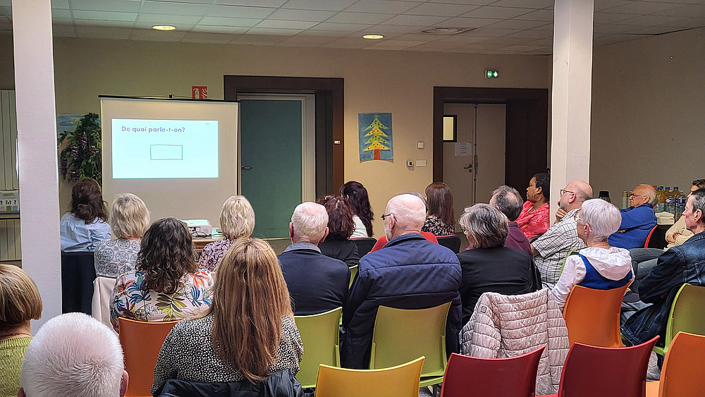Le personnel de l'établissement, des résidents et leurs familles, assistent à une présentation.