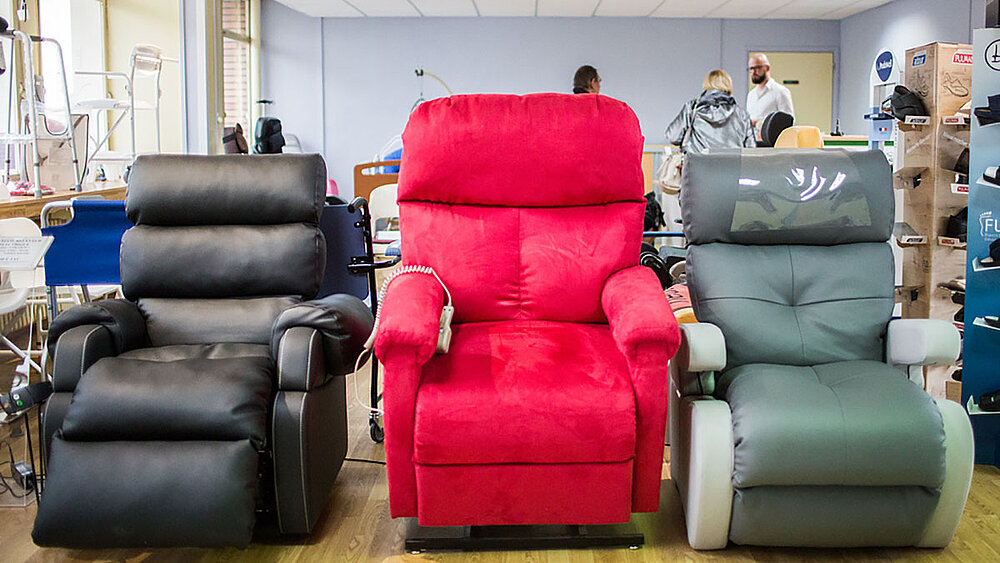 Trois fauteuils releveurs en exposition (un noir, un rouge, un gris)